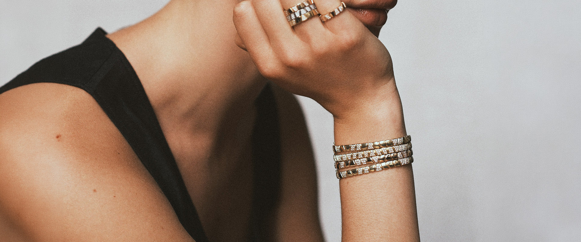 Femme portant une accumulation de bagues et de bracelets articulés en or 18 carats ornés de diamants éthiques par la maison de joaillerie Loyal.e Paris