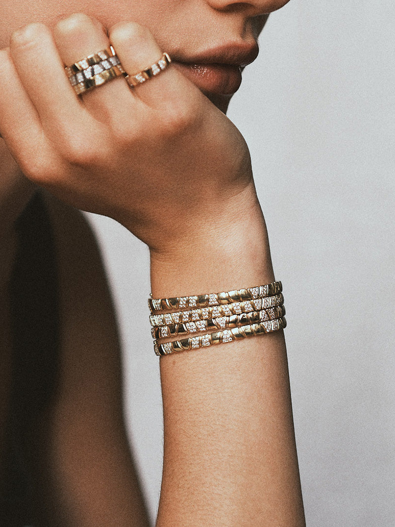 Femme portant une accumulation de bagues et de bracelets articulés en or 18 carats ornés de diamants éthiques par la maison de joaillerie Loyal.e Paris